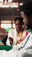 Vertical African American dentistry students examining teeth for upcoming exams, learning session on caries prevention using a jaw model in a library. Dedication to oral health education. Camera A. video