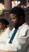Vertical Medical student reading a book and reviewing notes from the library database, focusing on medical research. Young man reflects dedication to healthcare career and academic goals. Camera A. video