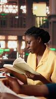 Vertical African american scholars reading course notes and comparing information at the library, studying for a test together using academic database for research. Educational materials. Camera A. video