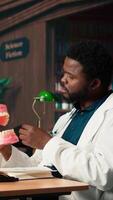 Vertical Medical student practices dentistry techniques with a plastic jaw model in a classic library, doing physical research for stomatology thesis. Developing professional skills for the career. Camera A. video