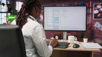 Coder at workstation programming on PC, writing lines of code, using development tools, feeling stressed. Woman in home office having deadline, stressed to finish debugging software, camera B video