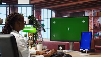 Remote employee in home office using green screen PC and mockup tablet to work on job tasks. Teleworker using chroma key computer monitor and isolated screen device to do job online, camera A video