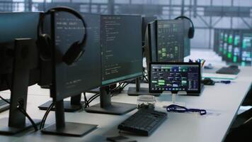Electronic devices in empty data center establishment monitoring hardware energy consumption. PC monitors on desk used for checking potential system failures in server room, handheld camera shot video