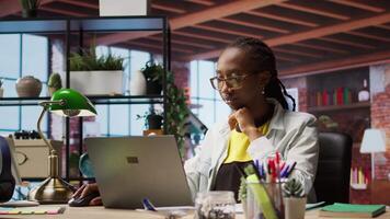 Teleworker using laptop in home office to crosscheck paper documents with online company files. Remote worker typing on notebook, inputting paperwork documentation data, camera A video