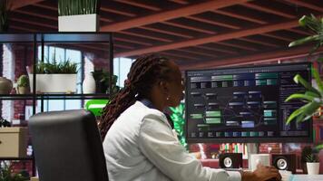 Teleworking computer scientist at home using PC to develop artificial intelligence self learning algorithms. African american woman working with AI machine learning software on PC, camera A video