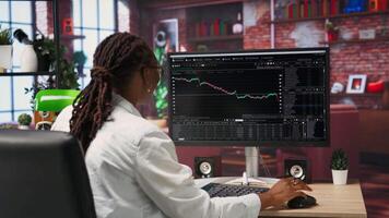 Excited day trader gaining money by selling stocks after browsing through documents to learn how to maximize profits. Thrilled investor celebrating financial gains earned from stock exchange, camera B video