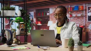 Woman enjoying leisure time at home, drinking coffee, texting friends on laptop. Cheerful person talking with mates on social network online website, using notebook, camera A video