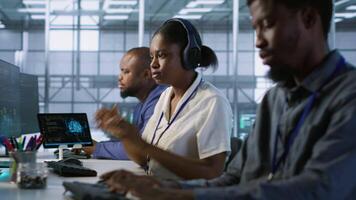 Engineer arrives in data center, puts headphones on, implementing AI systems. Server farm expert sitting down at desk, listening music and using artificial intelligence to prevent failures, camera A video