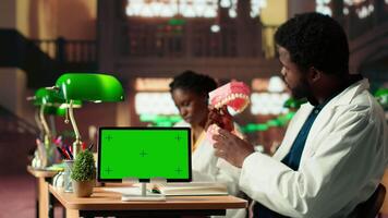 Medical student learns dentistry practices on a dummy jaw model next to mockup, developing dental qualifications through techniques. Study tools for exam preparations. Camera B. video