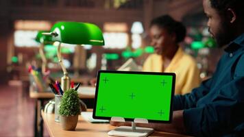 African american students consulting research papers next to green screen from the academic database, learning information from copy books. Young team of pupils at the library. Camera B. video