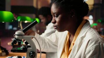 University student prepares for exam by researching cells and microorganisms under the microscope. Using books and papers from the academic database in the college library. Camera A. video