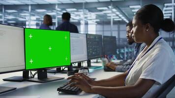 Software developer in server farm ensuring data remains shielded from potential threats using mockup PC. IT expert safeguarding data center against hackers with green screen computer, camera A video