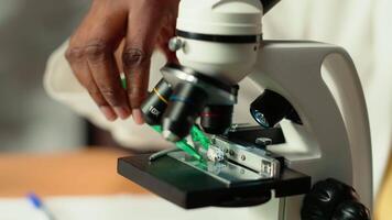 University student prepares for exam by researching cells and microorganisms under the microscope. Using books and papers from the academic database in the college library. Close up. Camera B. video