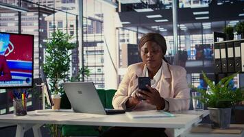 African american general manager answers smartphone call to discuss performance metrics, focusing on business development project. Director multitasking daily operations and analytics. Camera B. video
