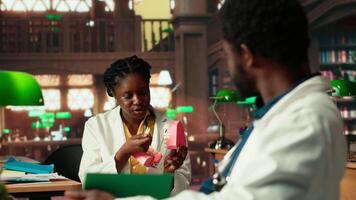 African American dentistry students examining teeth for upcoming exams, learning session on caries prevention using a jaw model in a library. Dedication to oral health education. Camera B. video