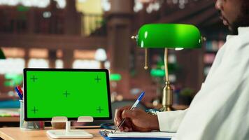 Future healthcare professional studies medical methods next to copy space screen in a campus library, reading case files and research papers. Black man works on academic growth. Camera B. video