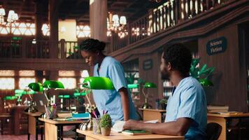 Black med school students team reading anatomy textbooks and class notes at the library, study group learning session. People focusing on exam preparation for a medical career. Camera A. video