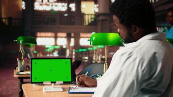 Future healthcare professional studies medical methods next to copy space screen in a campus library, reading case files and research papers. Black man works on academic growth. Camera A. video