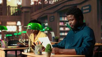 fast besluten elev framställning för prov på de campus bibliotek, använder sig av pedagogisk Resurser tycka om böcker, anteckningar och forskning papper för komplett information. tyst miljö för produktivitet. kamera b. video