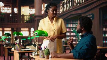 African American students reading their coursework in a quiet campus library, using academic resources and materials to help with educational development. Study time. Camera A. video