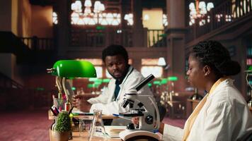 Female college student focuses on medical science by using a microscope, examining the chemical processes of microorganisms. Woman studying for her academic thesis paper. Camera A. video