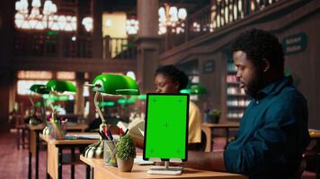 African american team studying for exams next to chroma key display, reading important information from copy books. Young university students use learning tools from database. Camera A. video