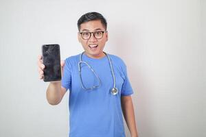 Male doctor in a white coat in a modern clinic reads information from a mobile phone corresponds with colleagues happy and smiles photo