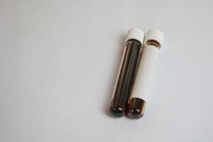 Laboratory worker's hand in rubber glove holding test tube with blood sample on light background with space for text photo