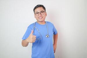 Middle age indian man wearing doctor coat and stethoscope doing happy thumbs up gesture with hand. approving expression looking at the camera showing success. photo