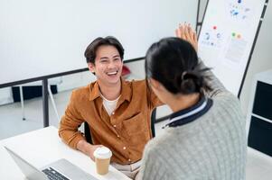 A smiling Asian man gives a high five to his colleague to celebrate their project's success. photo