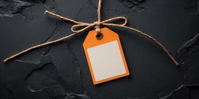 Blank Orange Tag Label with Jute String on Dark Textured Background photo