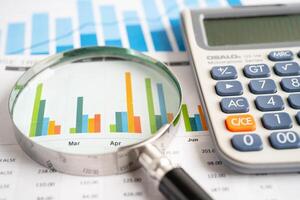 Magnifying glass with calculator on graph paper. photo