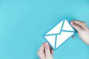 Paper letter on blue background, with copy space. Business concepts of online contact channels, electronic mail inbox notifications, and sending and receiving documents using online networks. photo