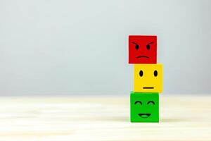 Stacked wooden cubes with emoticon faces according to color scale. Concept of satisfaction rating, customer evaluation, satisfaction survey. with copy space photo