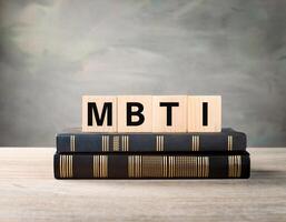 MBTI Acronym on Wooden Blocks with Books, Representing Psychological Study photo