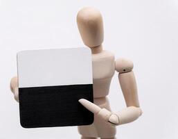 Minimalist Wooden Figure Pointing at Plaque with Contrasting Colors photo