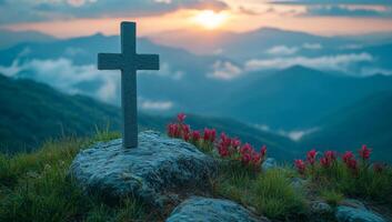 Cross stands on a mountain at sunset. A stone cross overlooks lush mountains with pink flowers as the sun sets behind the peaks, creating a serene atmosphere. photo