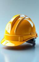 Yellow helmet on gray BG. A bright yellow construction helmet sits on a smooth gray surface, ready for use on a building site or project. photo