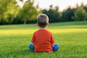 Child sitting peacefully on grass in a sunlit park during a calm evening photo