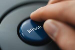 Hand pressing a blue button labeled peace with a focus on communication and harmony photo