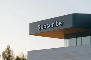 Large subscribe sign on modern building against clear sky during late afternoon. Rent the future, real estate for a subscription. photo