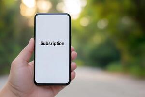 Hand holding smartphone displaying subscription details in a natural outdoor setting during daylight hours photo