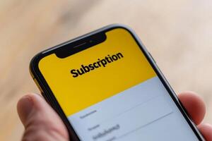 Engaging with a subscription service on a smartphone during a bright afternoon indoors photo