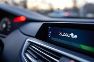 Digital display shows subscribe option in a modern car interior during evening drive on an urban road photo