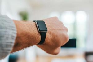 Modern smartwatch worn on a wrist in a contemporary indoor setting during daylight hours photo