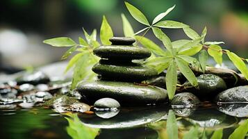 close up of a tower of smooth dark green stones stacked in a pile with water flowing down, in shallow water and a branch nearby photo