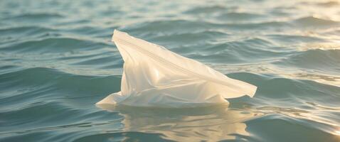 Plastic bag floating near the ocean surface illuminated by sunlight. photo