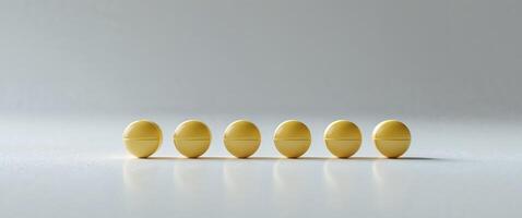 Four yellow pills are lined up on a white surface photo