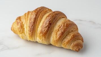 Freshly baked golden croissant with flaky layers resting elegantly on a marble surface photo