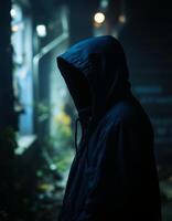 A man in a hoodie stands in the dark photo